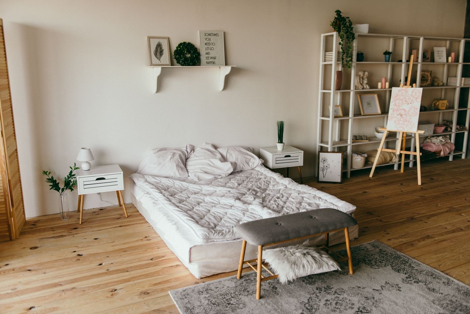 Modern minimalist bedroom with a low bed, wooden flooring and white shelf storage