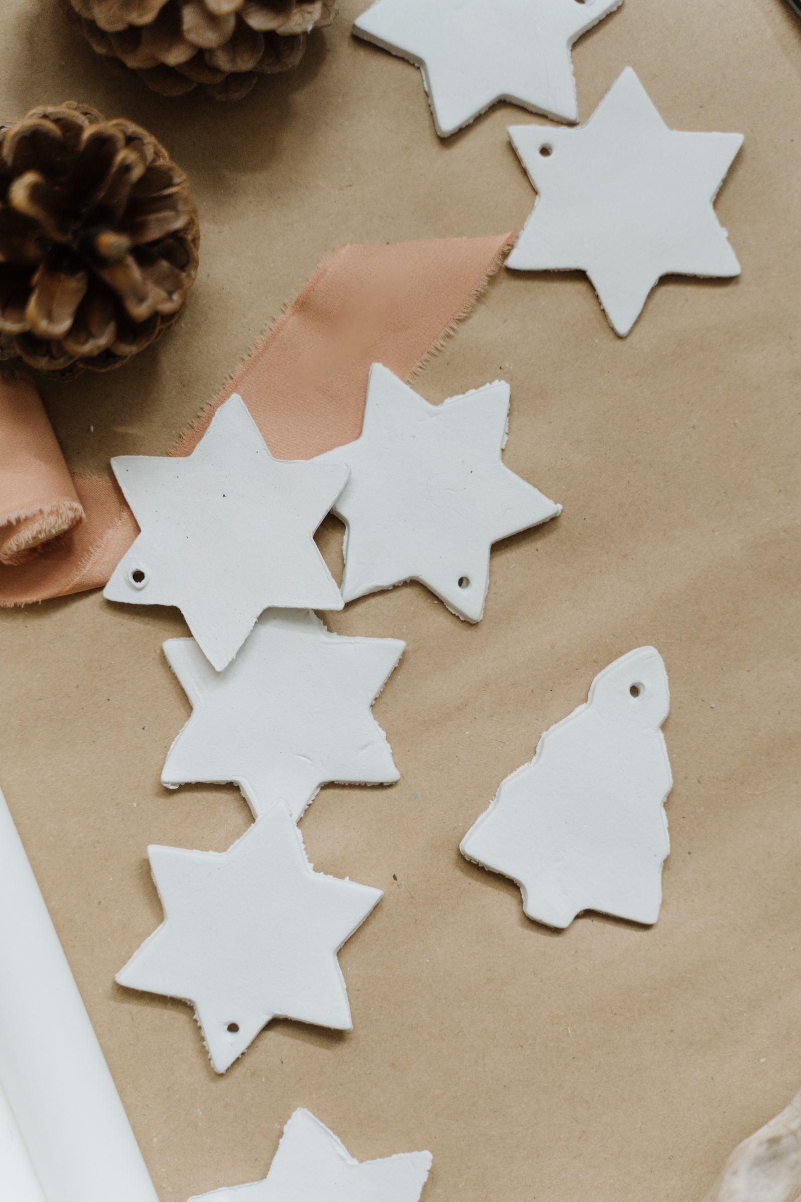 Flat lay of handmade paper star and tree ornaments on kraft paper with pine cones