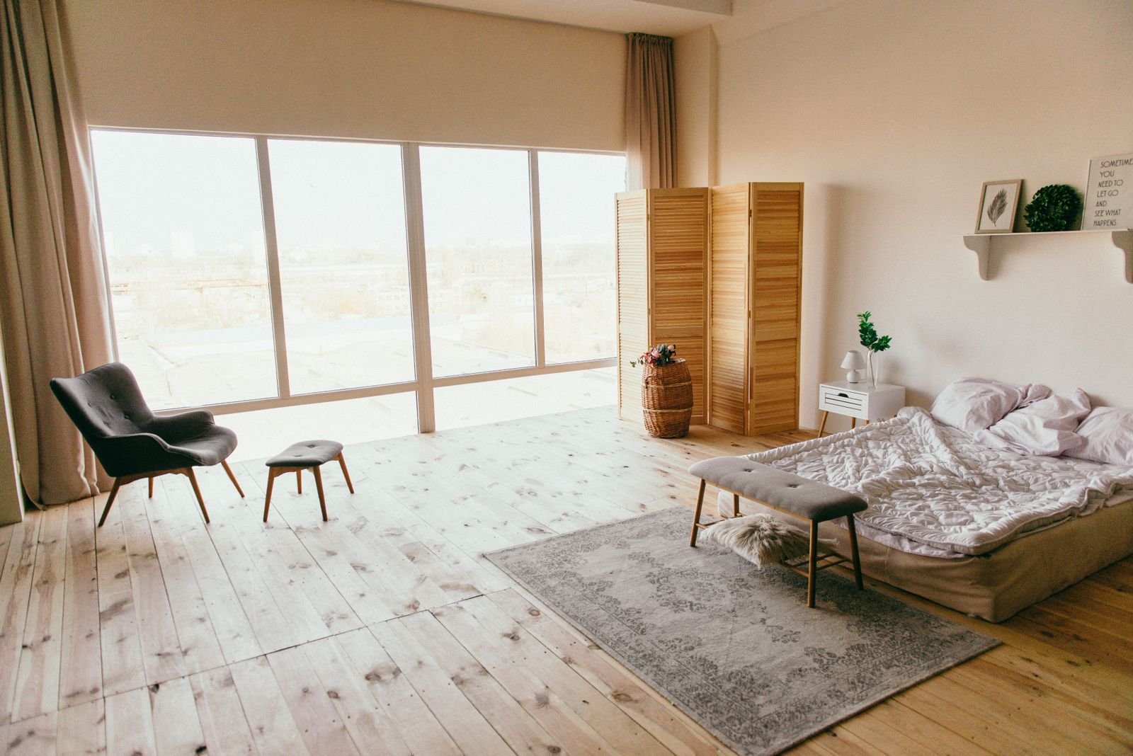 Elegant minimalist bedroom with wooden floors, large windows and simple furniture