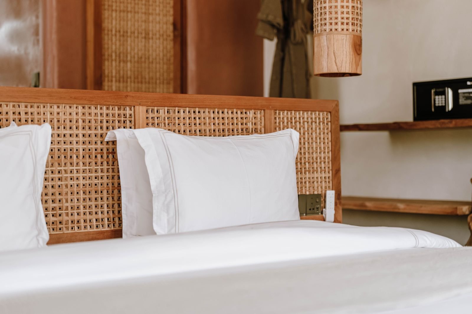Rattan bed with a woven rattan headboard and soft linen bedding in a calm, natural bedroom